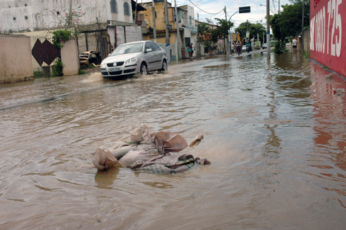 A Secretaria Municipal da Defesa Civil está distribuindo sacos de areia nas ruas que, em determinados trechos, estão alagadas, com a água saindo pelos bueiros (Foto: Check)