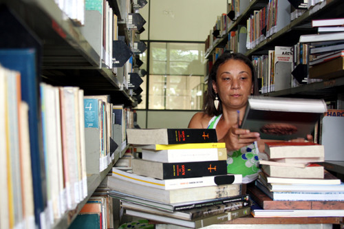 Bibliotecária Cristiane Mota mostra uma parte dos 371 livros recebidos da Biblioteca Estadual (Foto: César Ferreira)